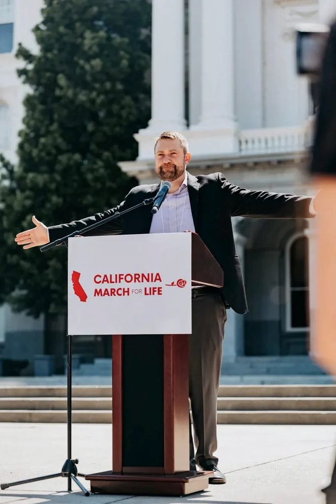 Jonathan R. Keller speaks with arms open at the California March for Life on the State Capitol steps in Sacramento