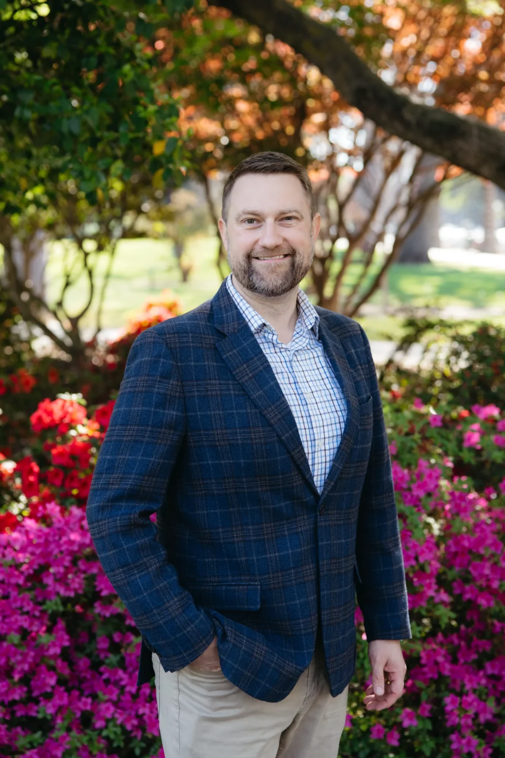 Jonathan R. Keller in a navy plaid blazer among blooming azaleas on the State Capitol grounds in Sacramento