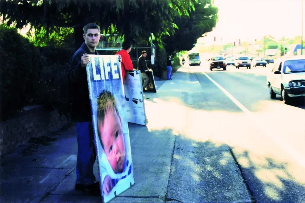 Jonathan Keller as a high school student holding a pro-life sign on a Sacramento street